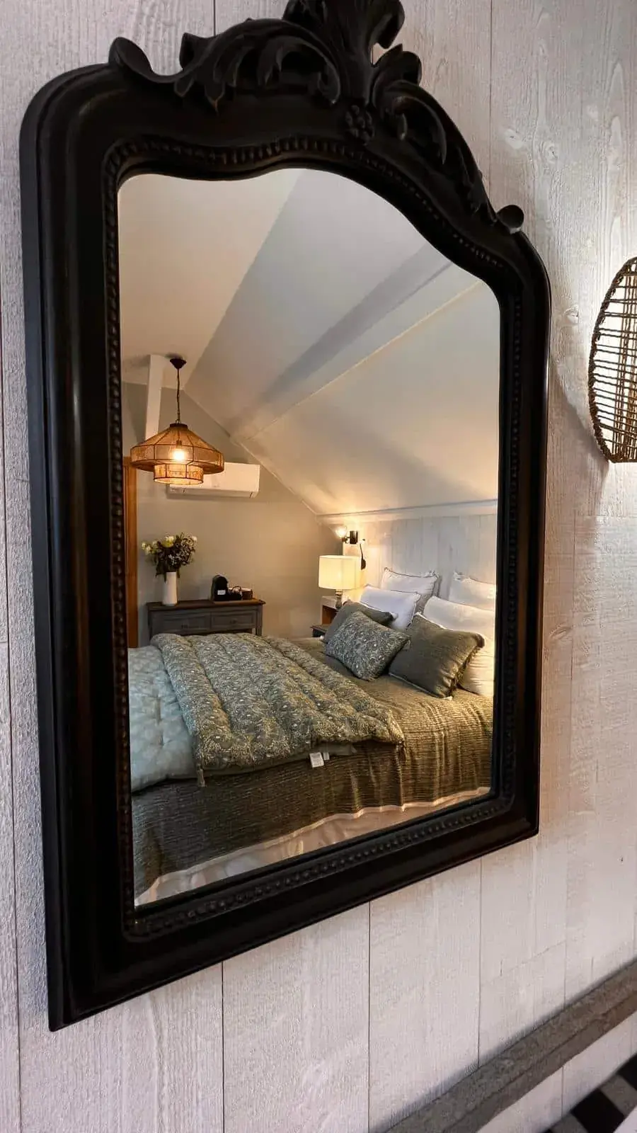 Une chambre de La Plonplonière vue dans un grand miroir ancien