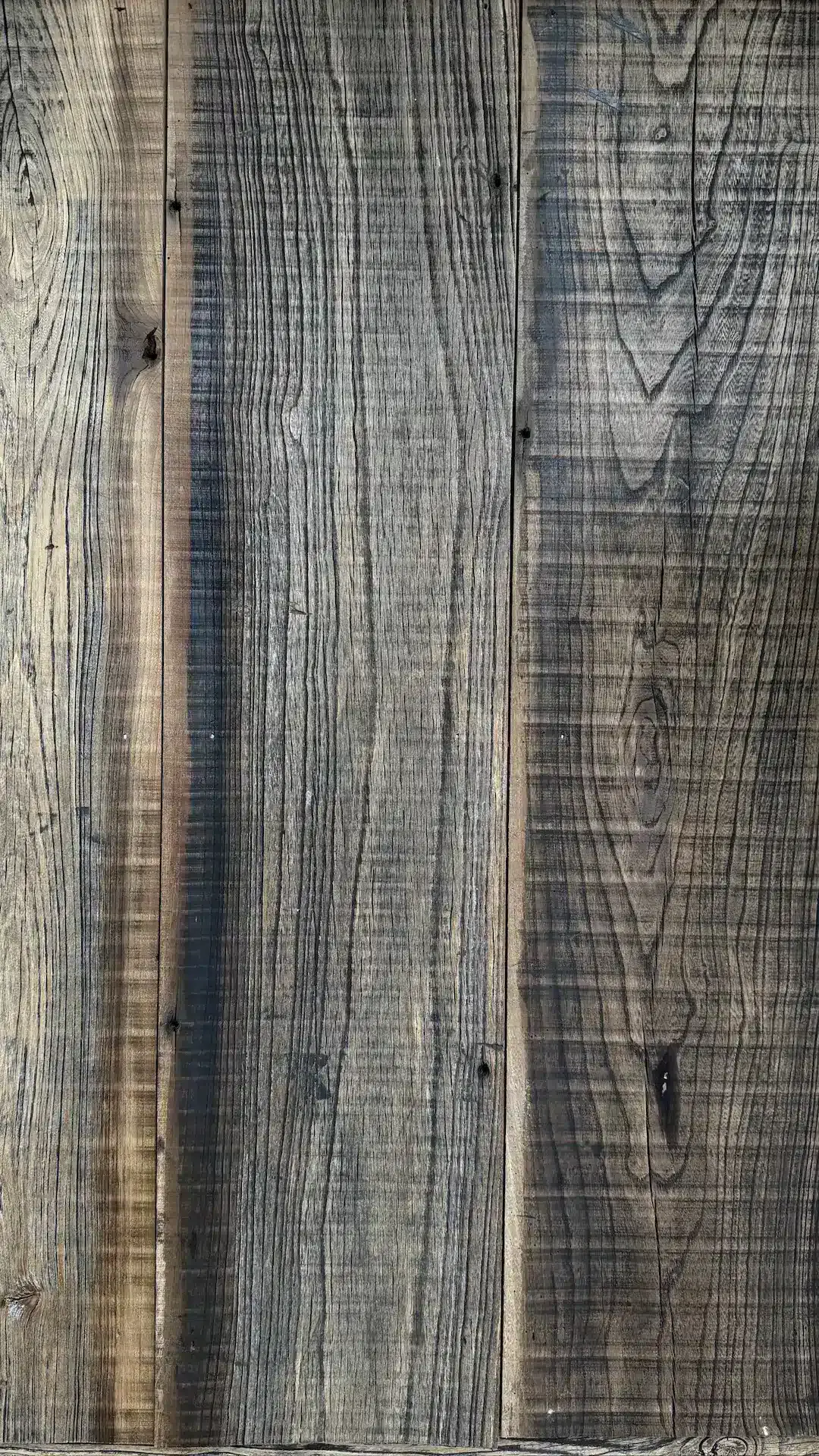 Gros plan sur trois planches de bois verticales dont les veines sont visibles et qui ont un aspect rustique, reflétant le charme naturel de La Plonplonière, Maison d'hôtes en Côte d'Opale.